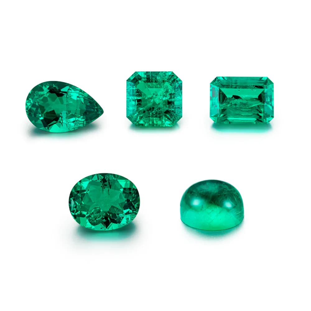 Green lab-grown colored gemstones in mixed cuts on a white background