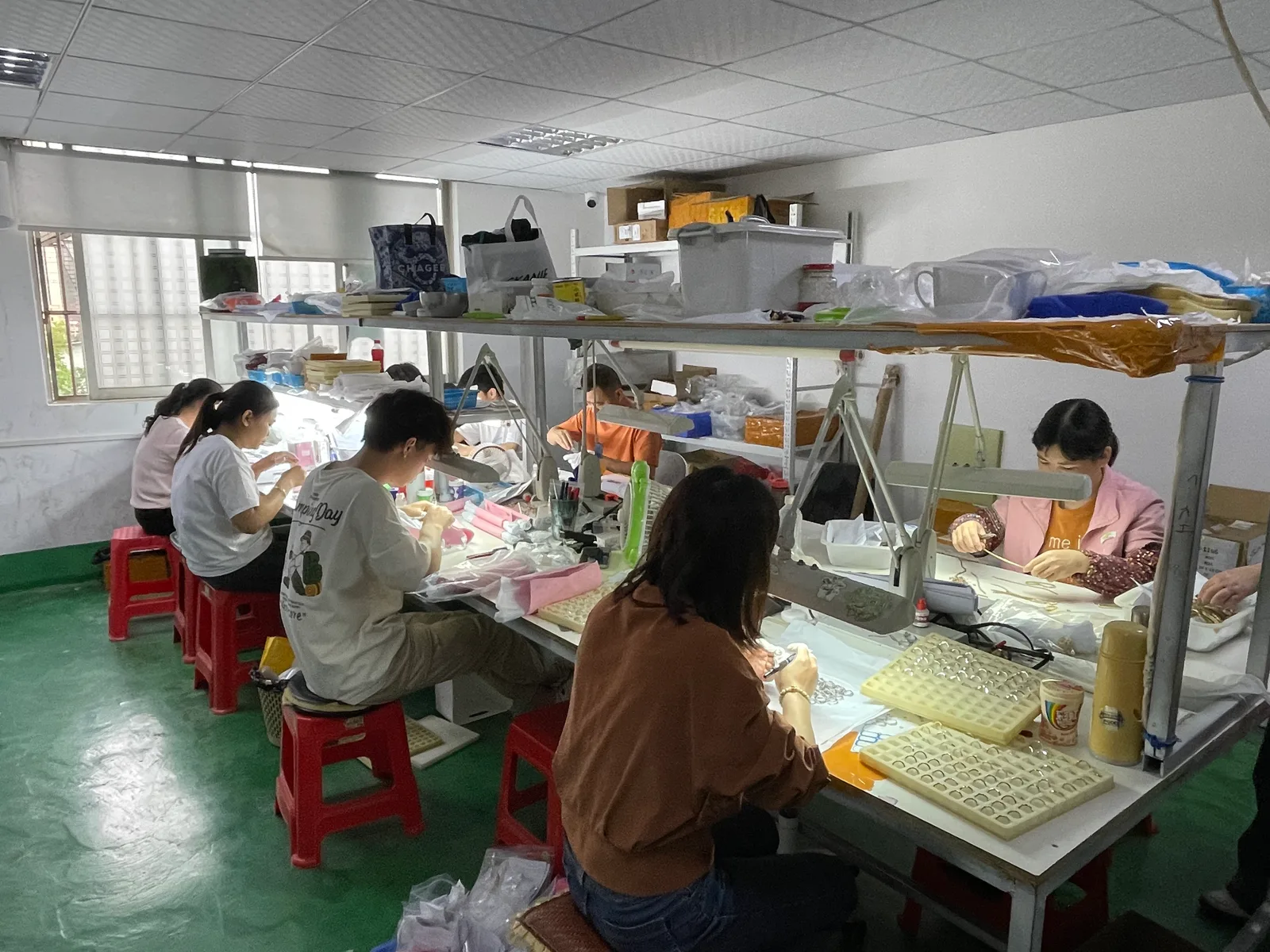 Jewelry setters working at illuminated benches during manual stone-setting production